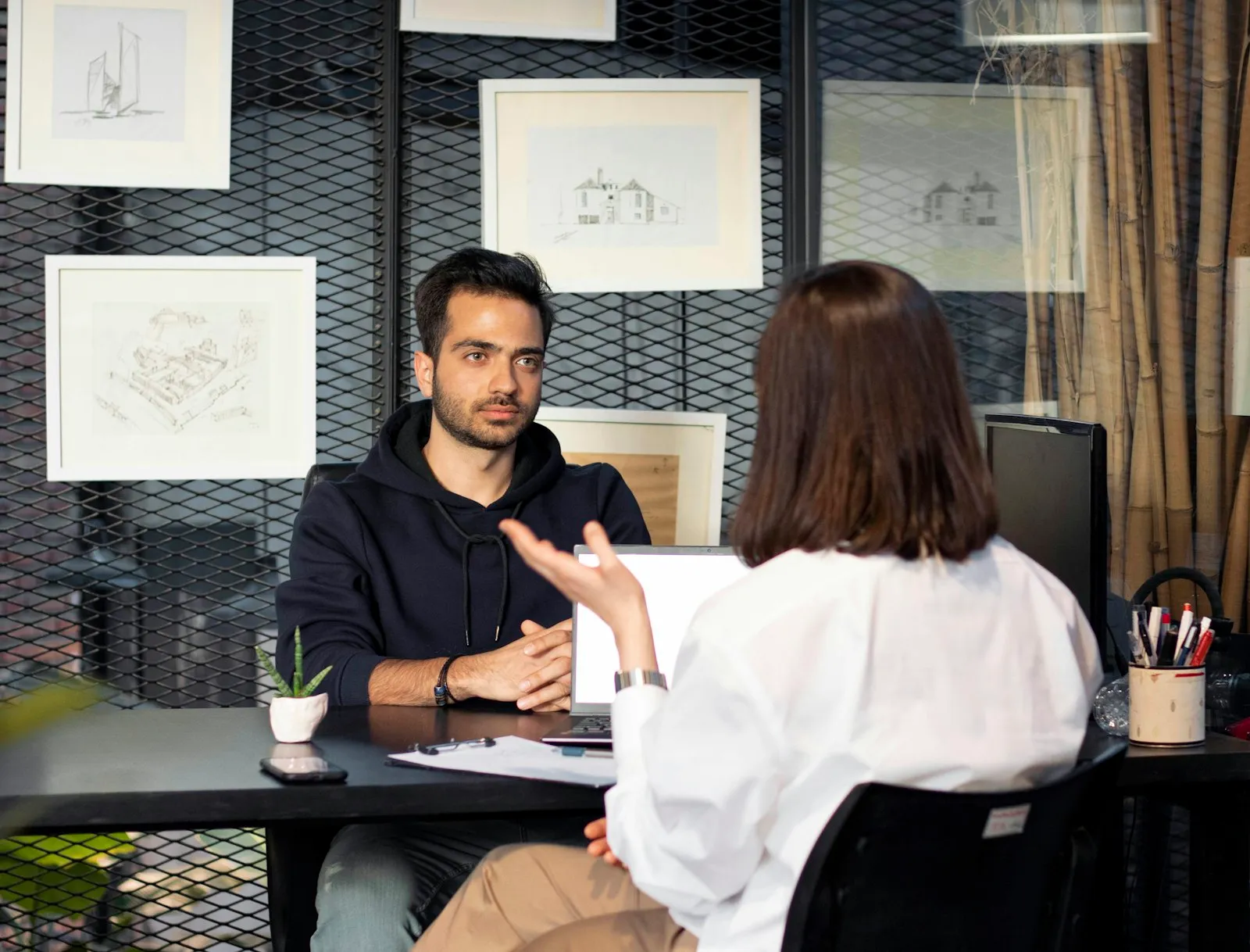 A candidate and interviewer in conversation at a desk in a creative office