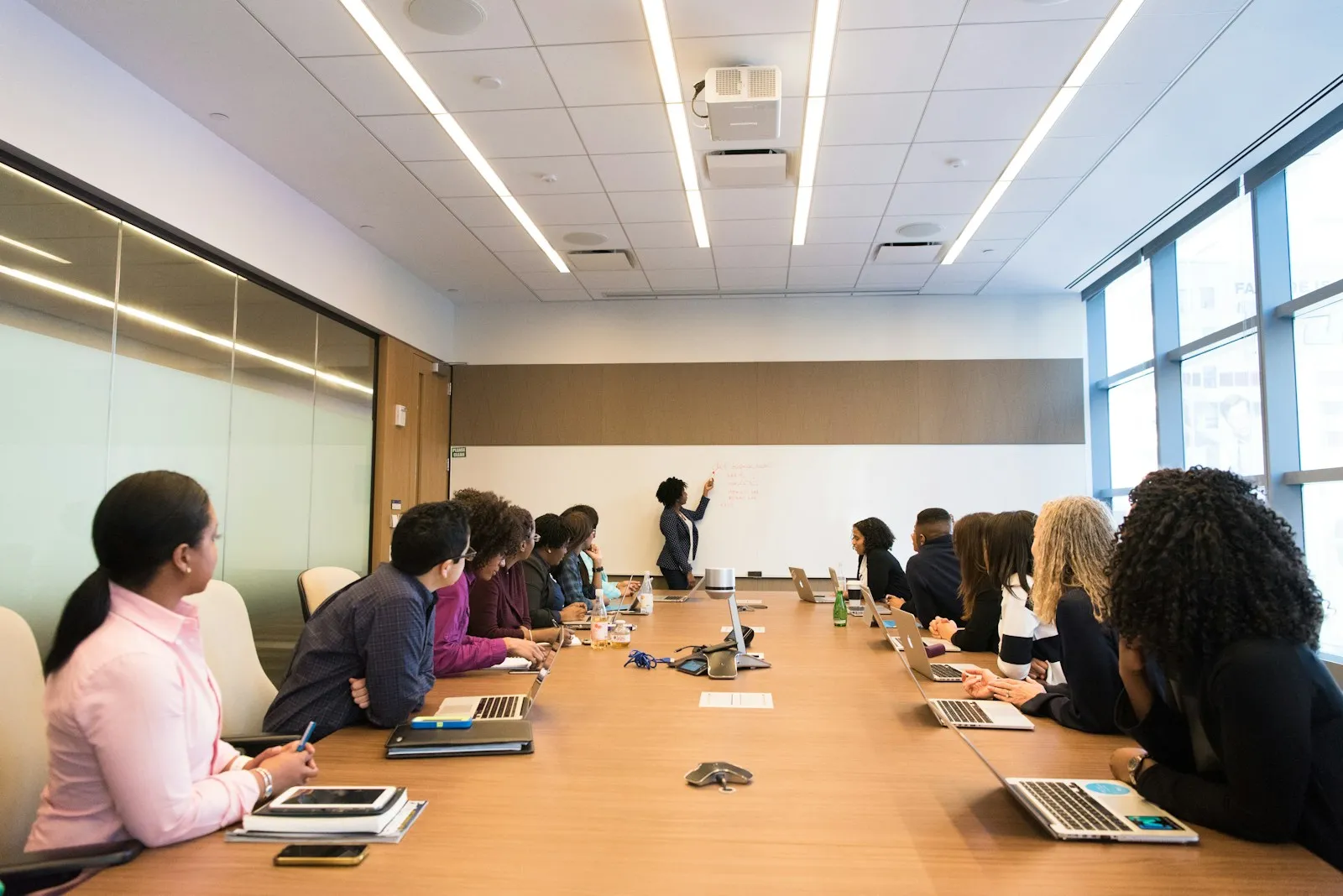 A presenter at a whiteboard leading a corporate training session in a conference room