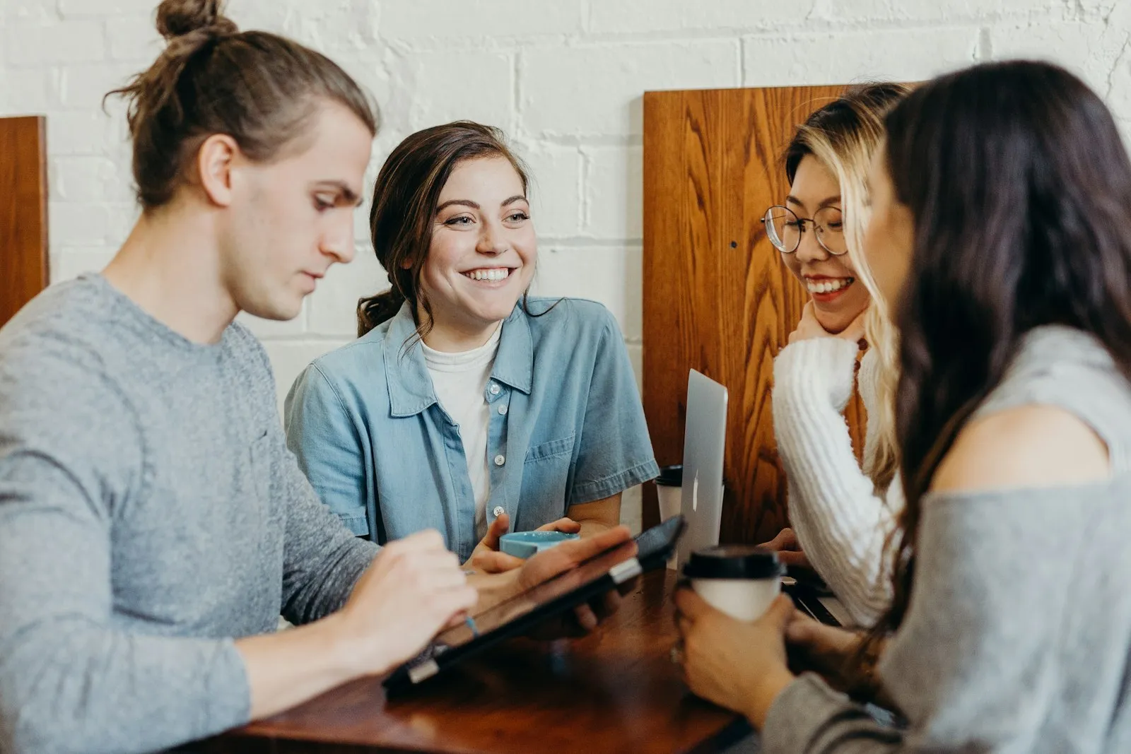 A relaxed, engaged team talking and smiling together over coffee in a casual workspace